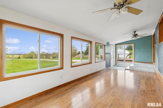 interior space with a ceiling fan, light wood-style floors, baseboards, and vaulted ceiling