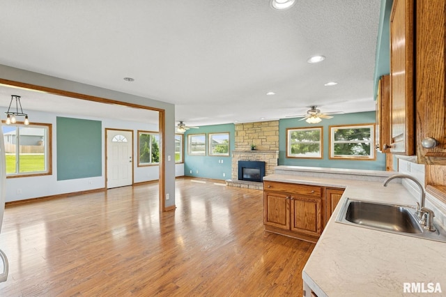 kitchen with a sink, a fireplace, open floor plan, and a ceiling fan