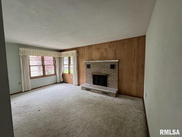 4528 5th St Unit B, East Moline, IL 61244 - unfurnished living room featuring wooden walls, baseboards, carpet, a brick fireplace, and a textured ceiling