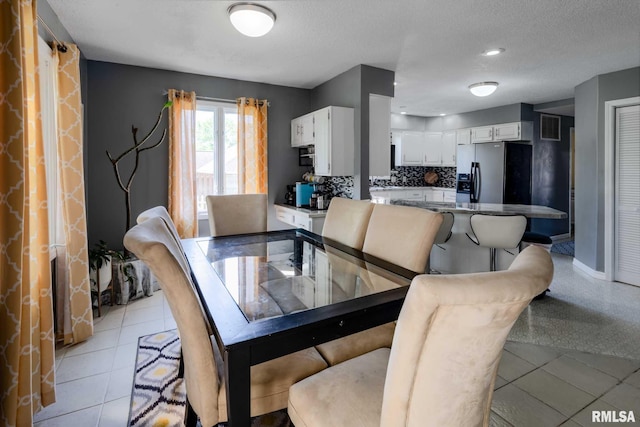 dining space with a textured ceiling, visible vents, and baseboards