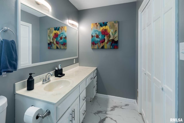 bathroom with vanity, toilet, baseboards, and marble finish floor