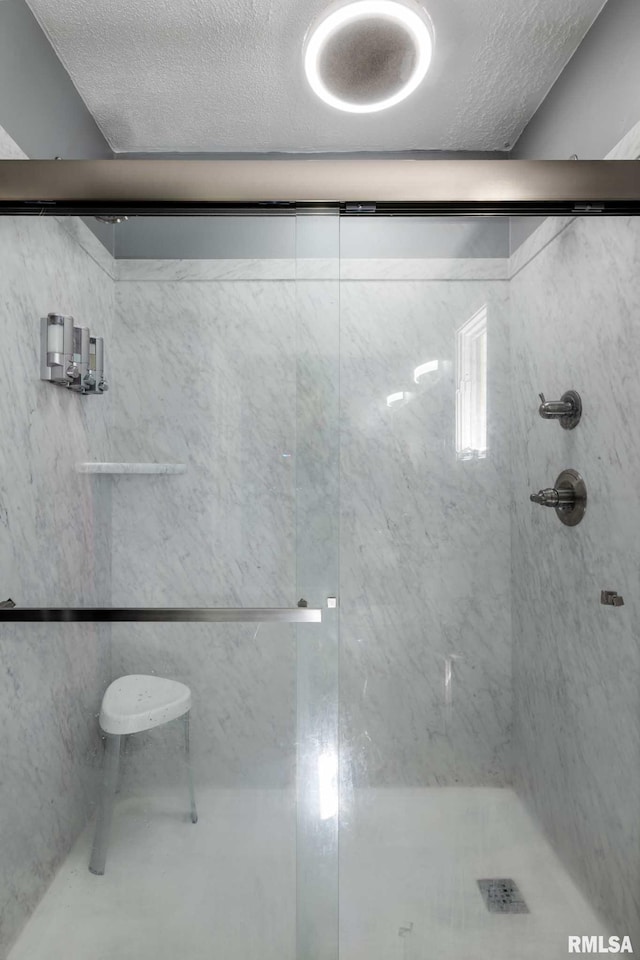 bathroom with a textured ceiling and a shower stall