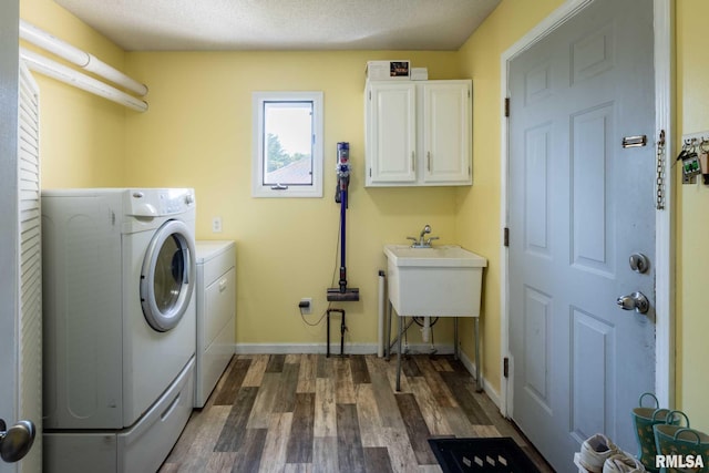 clothes washing area with a sink, cabinet space, washer and clothes dryer, baseboards, and dark wood-style floors