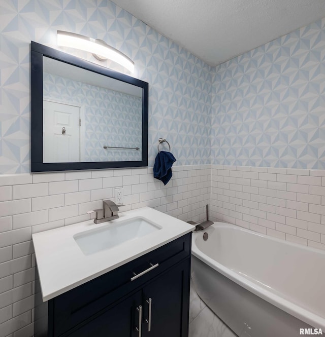full bath featuring tile walls, a garden tub, vanity, and a textured ceiling