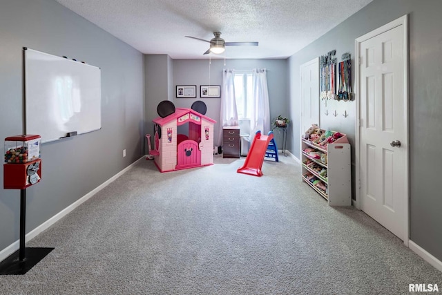 rec room featuring carpet, baseboards, a ceiling fan, and a textured ceiling