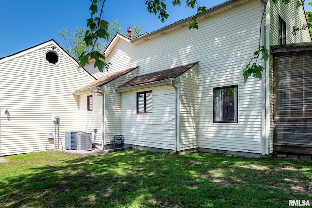 back of house featuring cooling unit and a lawn