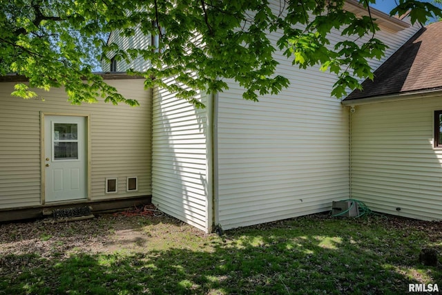 exterior space with roof with shingles and a lawn