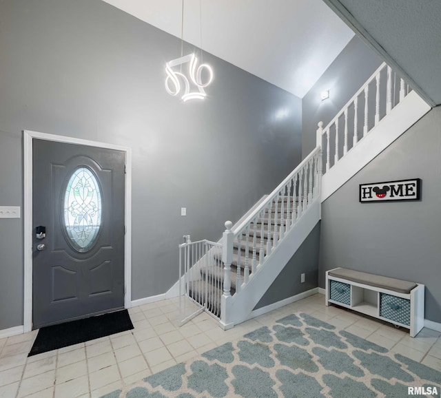 tiled foyer entrance with stairs, baseboards, high vaulted ceiling, and a notable chandelier