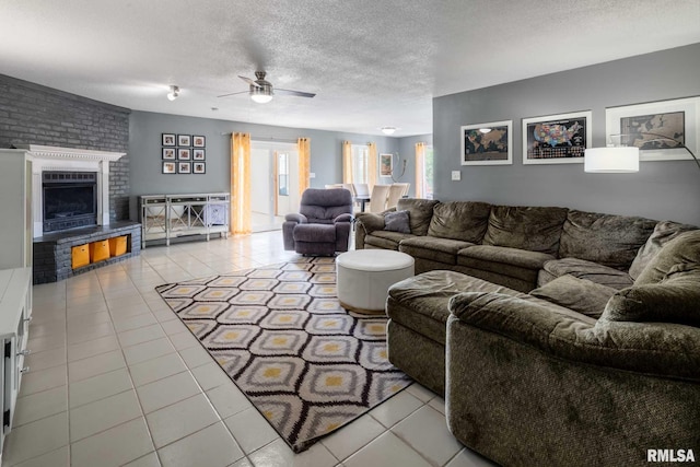 tiled living area with a fireplace, ceiling fan, and a textured ceiling