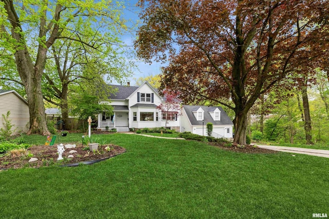 new england style home with concrete driveway, a front yard, and a porch