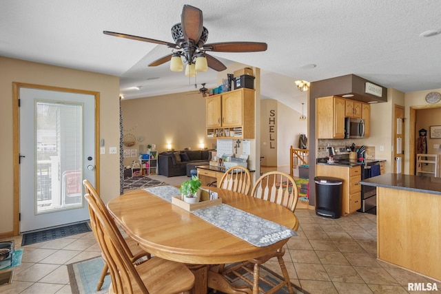 dining space with a ceiling fan, light tile patterned flooring, and a textured ceiling
