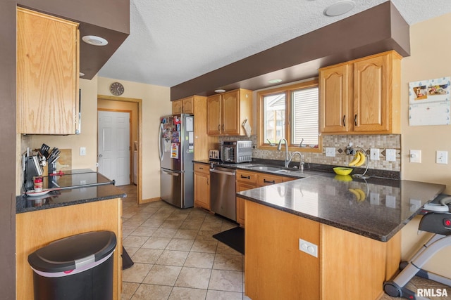kitchen featuring a peninsula, appliances with stainless steel finishes, tasteful backsplash, and a sink
