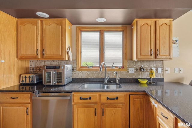 kitchen with backsplash, dark stone countertops, stainless steel dishwasher, and a sink