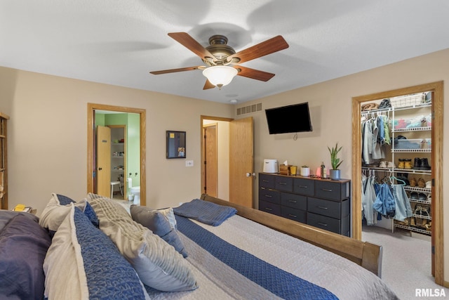 bedroom featuring a closet, carpet, ensuite bathroom, visible vents, and a walk in closet