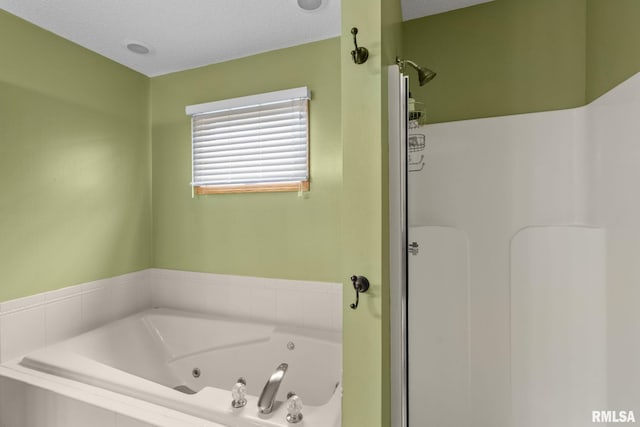 bathroom with a tub with jets and walk in shower