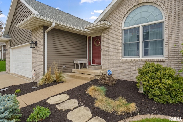 property entrance with roof with shingles, an attached garage, brick siding, and driveway