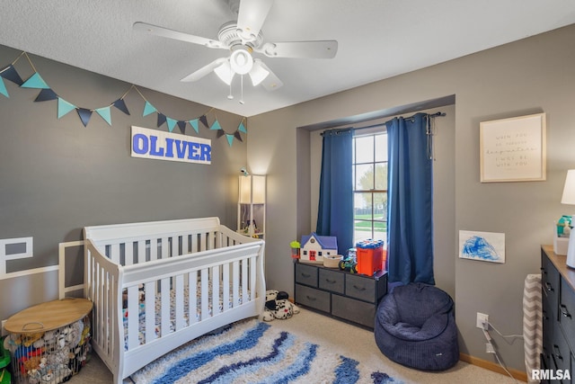 bedroom featuring carpet flooring, baseboards, a ceiling fan, and a crib