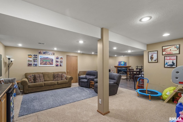 recreation room featuring carpet flooring, visible vents, a glass covered fireplace, and recessed lighting