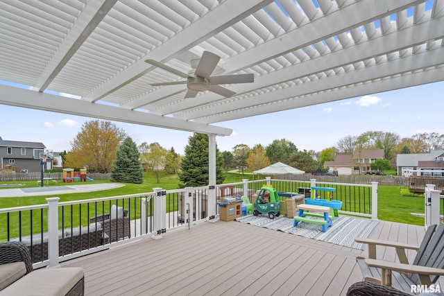 wooden deck featuring a yard, a ceiling fan, a playground, a pergola, and a fenced backyard