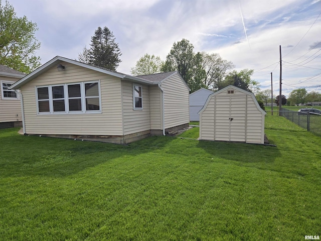 rear view of house featuring a yard, a storage shed, fence, and an outbuilding