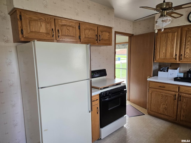 kitchen with freestanding refrigerator, brown cabinetry, range with electric stovetop, and wallpapered walls