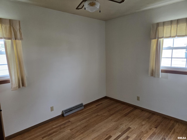 unfurnished room featuring ceiling fan, baseboards, visible vents, and wood finished floors