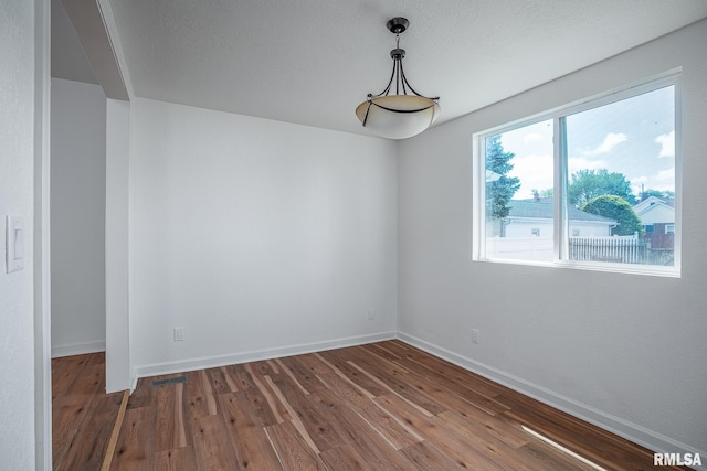unfurnished room featuring baseboards, visible vents, and wood finished floors