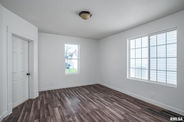 empty room with baseboards and dark wood finished floors