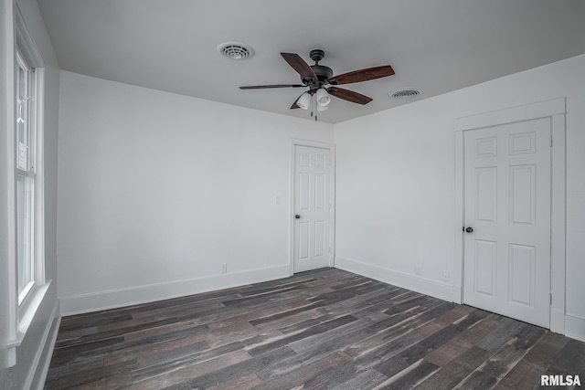 empty room featuring ceiling fan, baseboards, visible vents, and dark wood finished floors
