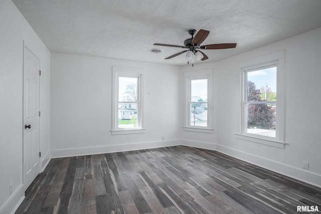 spare room featuring a textured ceiling, baseboards, and dark wood finished floors