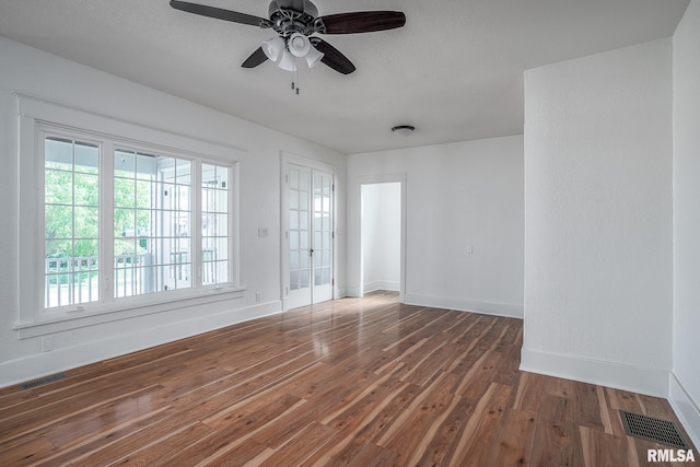 spare room with wood finished floors, visible vents, baseboards, and ceiling fan