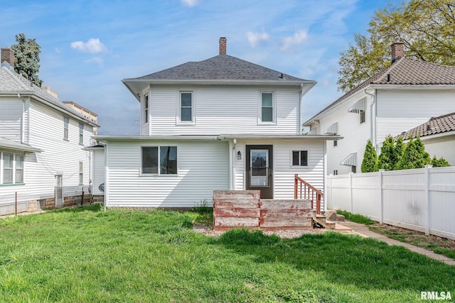 rear view of property featuring a chimney, fence, a lawn, and entry steps