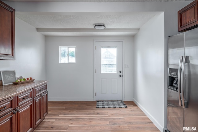 entryway featuring light wood-style floors, baseboards, and a textured ceiling