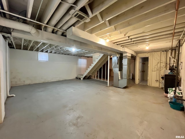 unfinished basement with heating unit, stairs, and visible vents