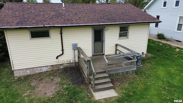 rear view of property featuring a shingled roof and a yard