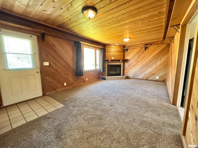 unfurnished living room with wooden walls, a fireplace, and wooden ceiling
