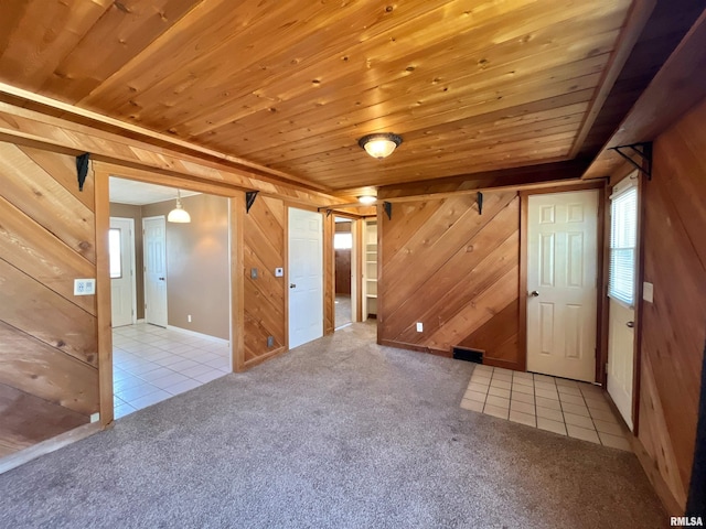 carpeted spare room featuring wooden ceiling, wooden walls, and tile patterned flooring
