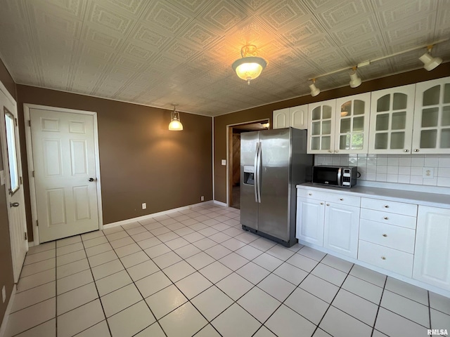 kitchen featuring light tile patterned floors, glass insert cabinets, white cabinets, light countertops, and appliances with stainless steel finishes