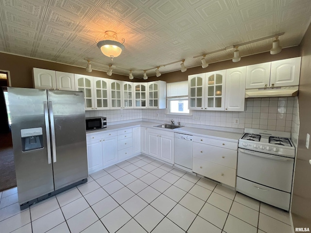 kitchen with track lighting, appliances with stainless steel finishes, under cabinet range hood, and a sink