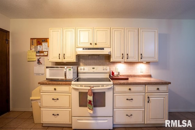 kitchen with a textured ceiling, under cabinet range hood, baseboards, white appliances, and tasteful backsplash