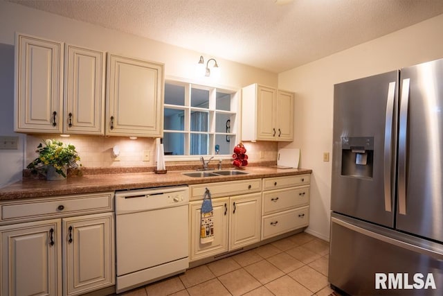 kitchen with light tile patterned floors, stainless steel fridge, a sink, backsplash, and dishwasher