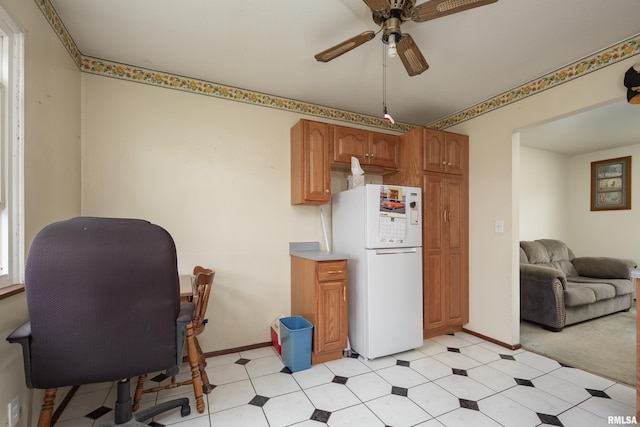 kitchen featuring freestanding refrigerator, baseboards, a ceiling fan, and brown cabinets