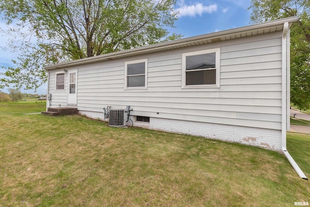 back of house with central air condition unit and a yard