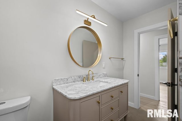 bathroom featuring vanity, toilet, baseboards, and wood finished floors