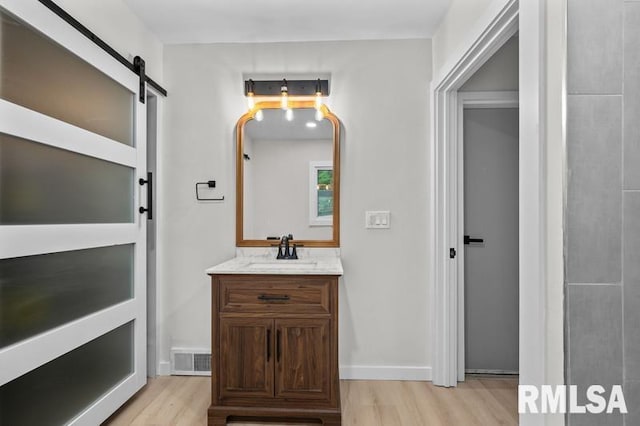 bathroom with vanity, baseboards, visible vents, and wood finished floors