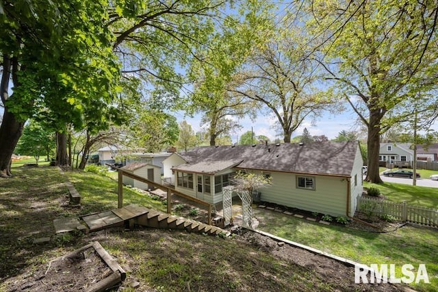 rear view of property with a yard, a sunroom, and fence