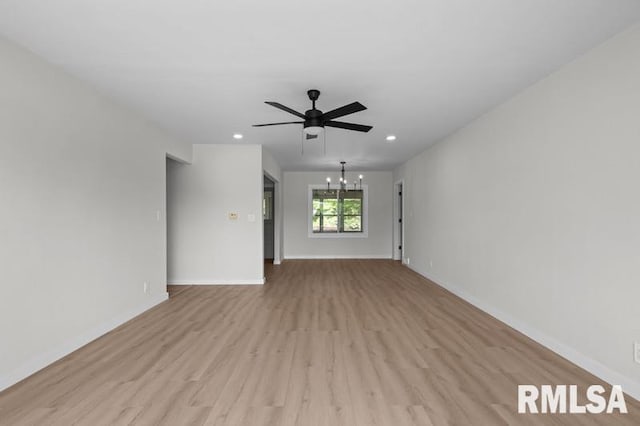 unfurnished living room featuring baseboards, light wood-type flooring, and ceiling fan with notable chandelier