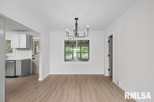unfurnished dining area featuring baseboards, visible vents, an inviting chandelier, and light wood-type flooring
