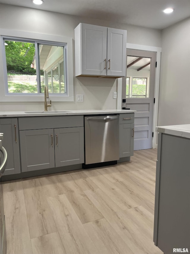 kitchen featuring light countertops, light wood-style flooring, a sink, dishwasher, and gray cabinetry