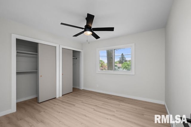 unfurnished bedroom with baseboards, two closets, and wood finished floors